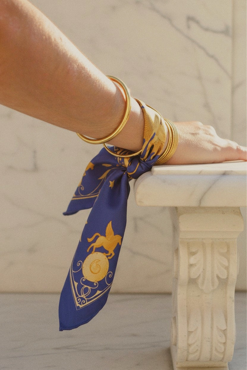 Foulard en soie pour femme noué au poignet, inspiré de l'antiquité grecque et de la mythologie pour les amoureux de la Méditerranée.