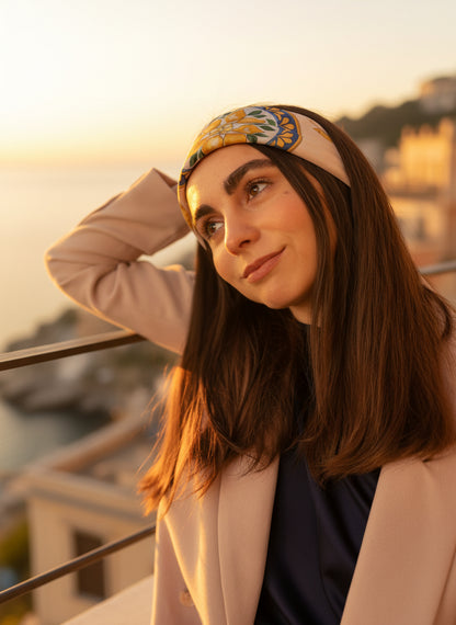 Carré de soie Capri Eleganza blanc porté en bandeau dans les cheveux, avec vue sur l'île de Capri