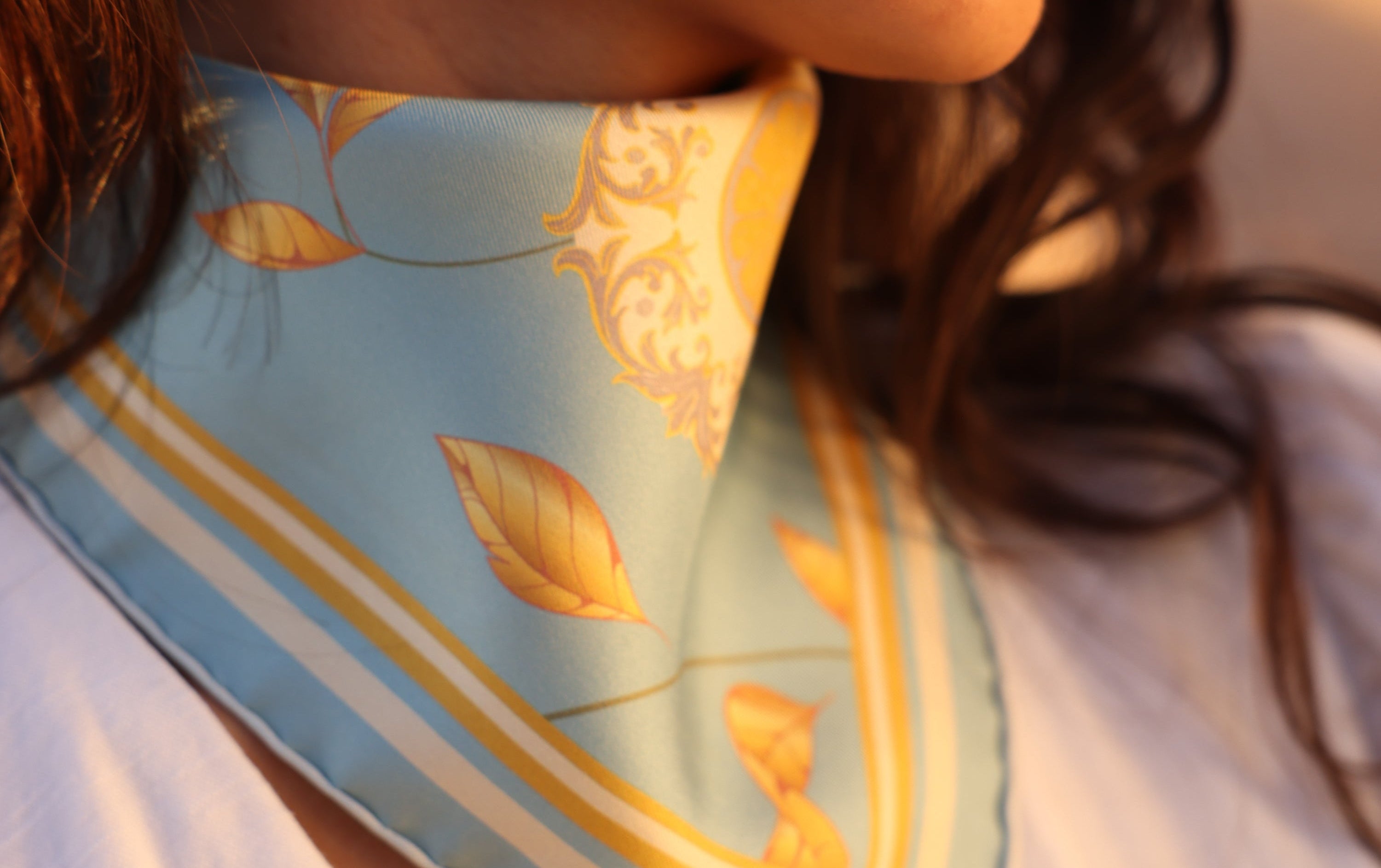 Vue détaillée du foulard en soie Capri Eleganza Bleu, avec de la lumière dessus et avec des motifs dorés.