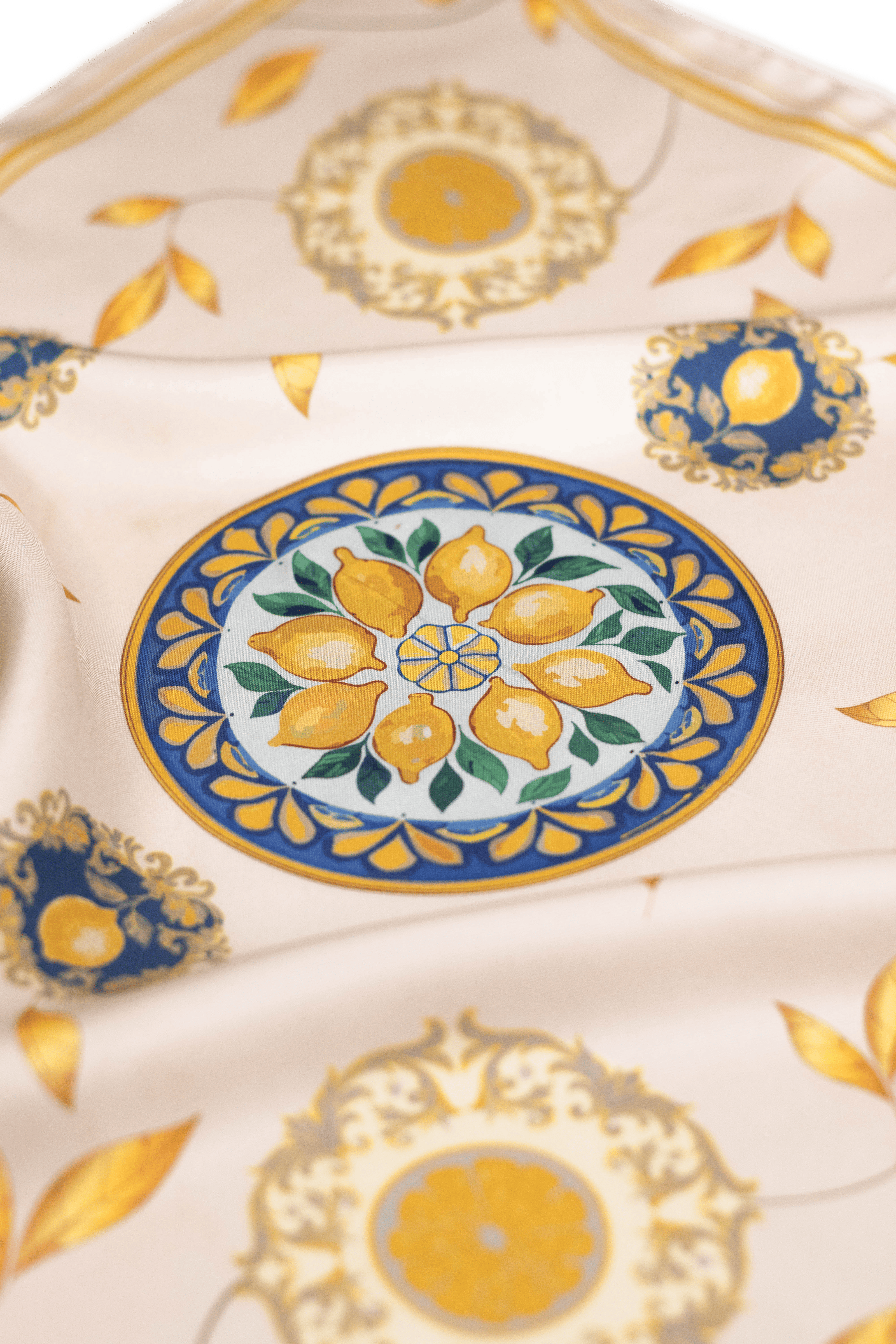 Vue détaillée du foulard Capri Eleganza Bleu, avec des motifs de citrons, des feuilles dorées et des références à la céramique de l'île. 